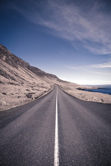 Asphalt road on the shore of the fjord in the east of Iceland. Toned