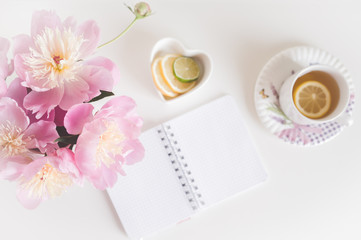 Obraz na płótnie Canvas Bouquet of peonies, tea with lemon, notebook , photo in gentle colors. Good morning. Have a nice day! Place for text