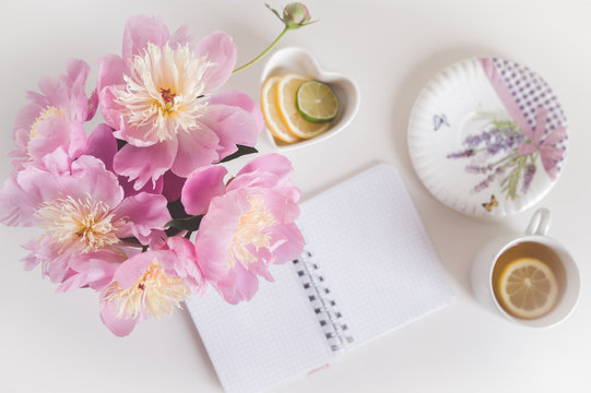 Bouquet of peonies, tea with lemon, notebook , photo in gentle colors. Good morning. Have a nice day! Place for text