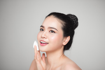 Happy smiling beautiful asian woman using cotton pad cleaning skin.
