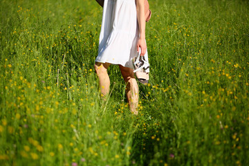 Walking woman in green grass, field, natural background, female legs, white dress