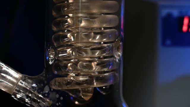 Crystal Spiral. Spiral glass tube with water close up. Glass spiral pipe from the reflux condenser with running water. fluid filtration in the laboratory experiment