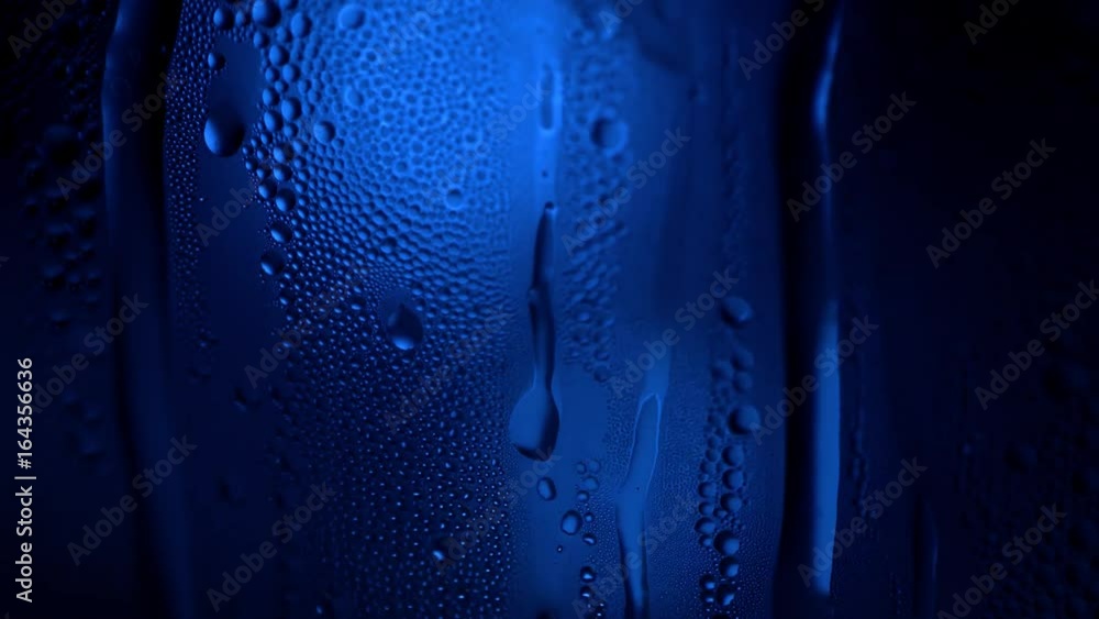 Poster a drop of water on a glass close-up macro with sparkling bokeh on blue blurred background. abstract 