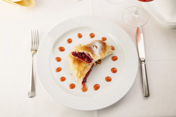 Cherry pie slice arranged on a plate, Wineglass in background, Traditional dessert in elegant setting, Selective focus with soft light