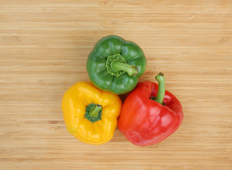 Green , red and yellow bell pepper on wood background.