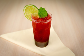 Strawberry cocktail with lime and mint on wooden table