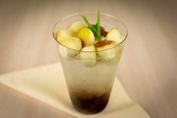 Lemonade with apple pieces on wooden table 