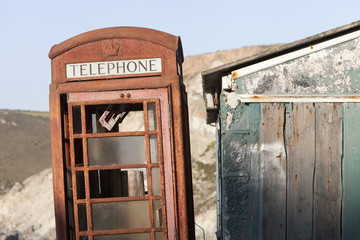 A derelict red phone box next to a dilapidated building