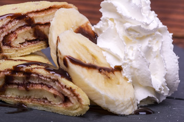 crepe with banana and chocolate on round slate stand