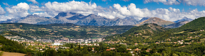 Fototapeta na wymiar The city of Gap in the Hautes Alpes with surrounding mountains and peaks in Summer. Panoramic. Southern French Alps, France