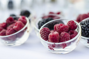 Ripe raspberries with blackberries in a glass cup