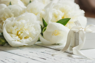 Bouquet of white peonies and present box on the wooden table