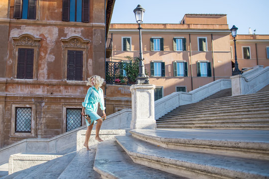Young attractive blond woman barefoot
сlimbs the stairs in spanish steps in Rome 