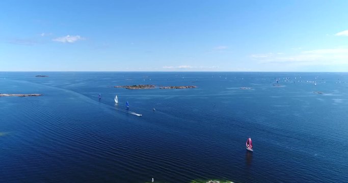 Speedboats on baltic sea, Cinema 4k aerial landing view towards a motorboat bypassing sailboats, out on the turquoise sea, on a summer hango regatta day, in the finnish archipelago of Hanko, Finland