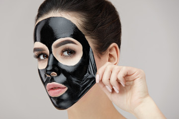 Woman Face Mask. Closeup Beautiful Girl Removing Black Mask