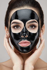 Woman Face With Natural Makeup And Black Peeling Mask On Skin