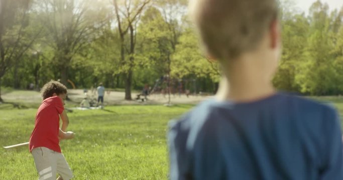 Two little boys are playing baseball with a wooden stick outside