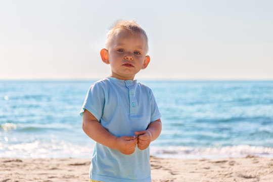 Portrait of astonished little blonde boy on beach