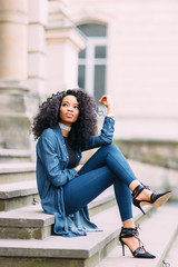 Young african american girl in jeans posing near old building