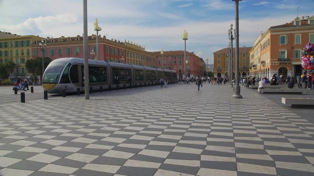 Passengers running along Place Massena to bus stop to get on speed tramcar