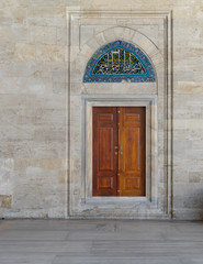 Fototapeta na wymiar Wooden engraved door on stone wall and tiled marble floor, Sulaymaniye Mosque, Istanbul, Turkey