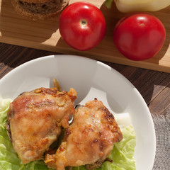 Two toasted chicken steaks on a plate and tomatoes with pepper and bread on a board, for breakfast or for lunch