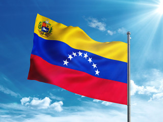 Venezuela flag with coat of arms waving in the blue sky