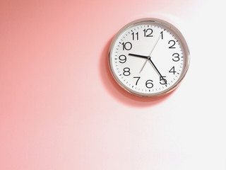 White clock on pink concrete wall