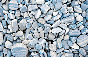 Abstract grey dry round stones background. At the beach. Sea pebbles and gravel style. Top view. Close up.
