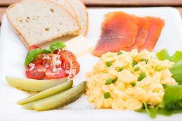 Breakfast set, scrambled eggs with chives, fish, cucumber, tomato and bread