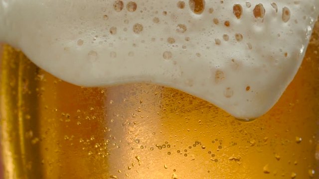 Glass of beer close-up with froth in slow motion