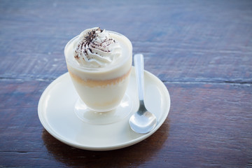 Delicious milk pudding with grated chocolate over napkin on wood table
