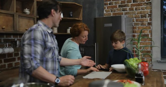 Happy Family In Kitchen Cooking Food While Son Filming Video Of Parents And Sister Preparing Meal Together Slow Motion 60