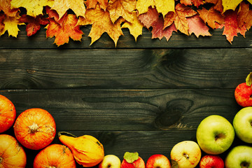 Autumn leaves, apples and pumpkins over wooden background