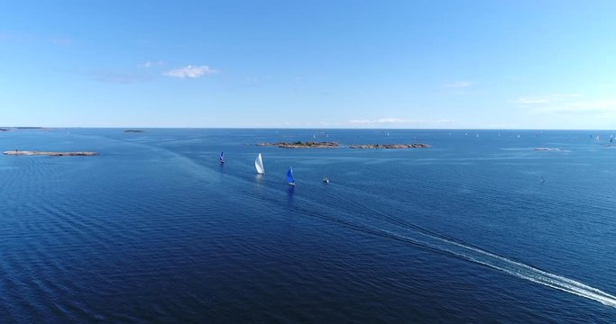 Sailboats on baltic sea, Cinema 4k aerial view of a motorboat and colorful sailboats, out on the turquoise sea, on hango regatta day, in the finnish archipelago of Hanko, Finland