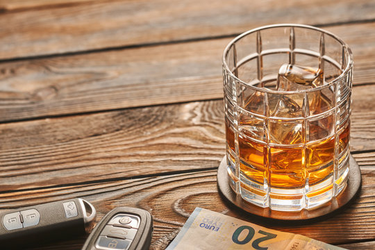 Glass of whiskey or alcohol drink with ice cubes and car key. Drink and drive concept.