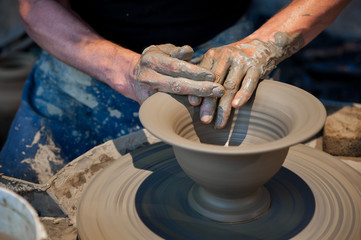 Working gray clay on pottery wheel