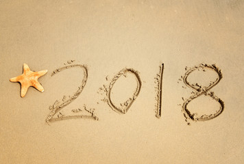 2018 written in sand write on tropical beach