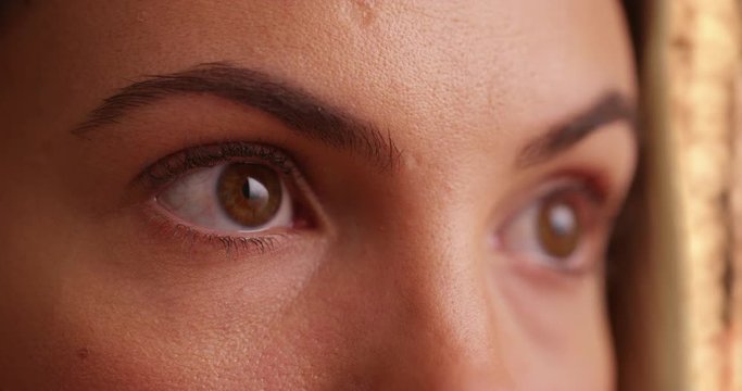 Close up of female millenial's eyes blinking outdoors. Close-up of young woman's brown eyes looking off camera outside. 4k 