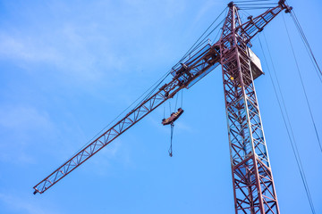 Construction site in the city, crane and the incomplete building on blue sky