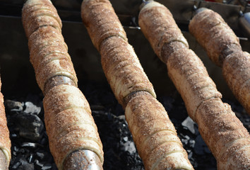 Cooking (baking) appetizing delicious straw on a spit on an open fire, street food, Czech cuisine, trdelnik.