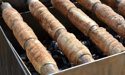 Cooking (baking) appetizing delicious straw on a spit on an open fire, street food, Czech cuisine, trdelnik.