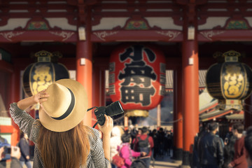 Tourist is travelling at Kaminarimon (The gate of Sensoji Temple). It has kanji written in black on a big red paper lantern means Thunder Gate. This place is a famous landmark in Asakusa ,Tokyo,Japan.