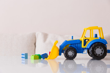 Fototapeta premium Closeup of children toy tractor with colorful plastic bricks or details on white background. Baby's toys on the table isolated.
