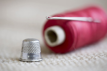 Hobby, diy concept - old needle, red thread and thimble
