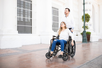 Obraz na płótnie Canvas Man pushing woman on a wheelchair