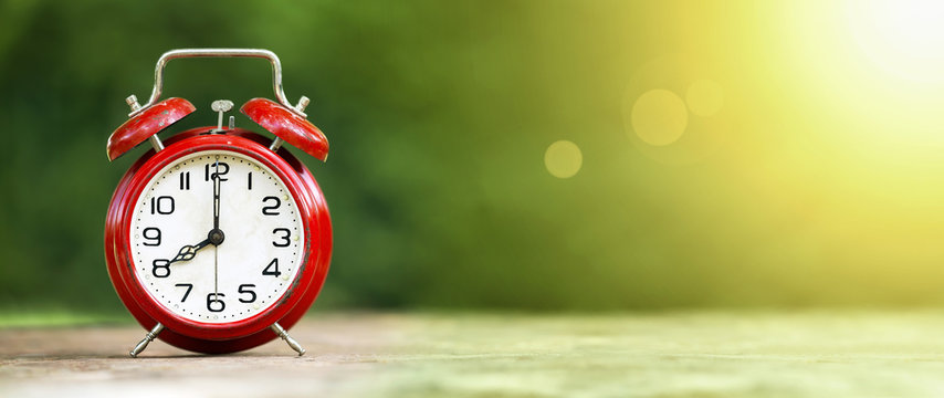 Summertime - web banner of a retro red alarm clock on green background
