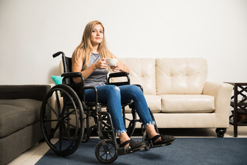 Fototapeta na wymiar Sad woman on wheelchair relaxing at home