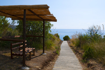 Calabria: una panchina all'ombra in una giornata d'estate sul sentiero che porta alla spiaggia dell'Arco Magno, piccola baia nascosta con un arco naturale scavato dalle onde durante i secoli