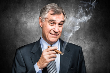 Confident senior businessman smoking a cigar - obrazy, fototapety, plakaty